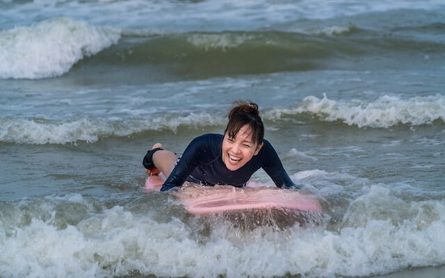 由比ヶ浜のサーフィン体験で女性が波に押されている様子