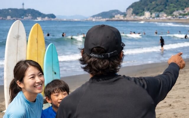 由比ヶ浜で親子が初心者向けサーフィン体験をする様子